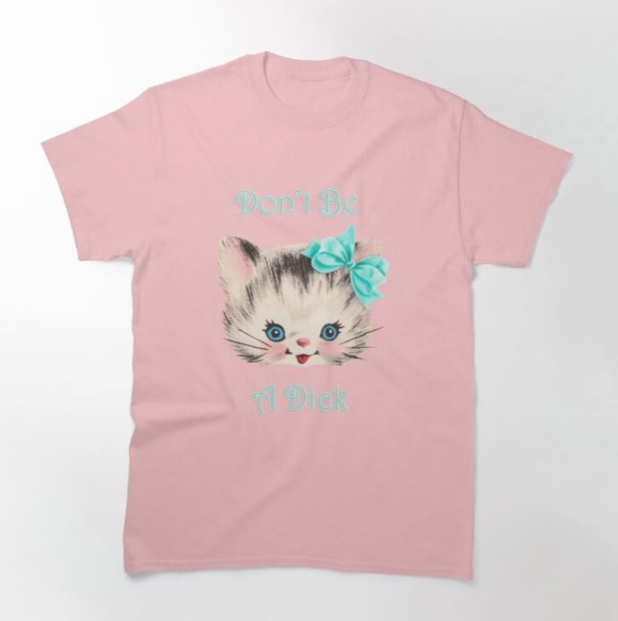 A light pink medium-sized T-shirt by Blue Dog Posters, featuring an illustrated cat face wearing a teal bow. The text "Don't Be A Dick" is written around the cat in light blue script. This product is called the "Cat Don't Be A Dick T-shirt Pink MED.