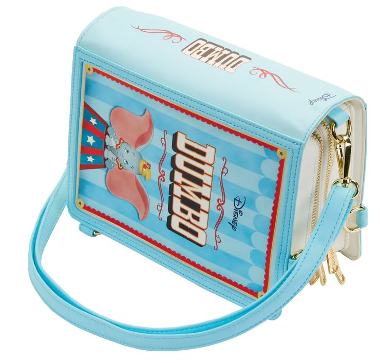 The Dumbo 1941 Book Convertible Crossbody by Blue Dog Posters is a light blue handbag with a vertical graphic of Disney's Dumbo. Crafted from vegan leather, the design mimics a circus poster with stripes, stars, and the name "Dumbo" prominently featured. It has a blue handle and gold hardware.