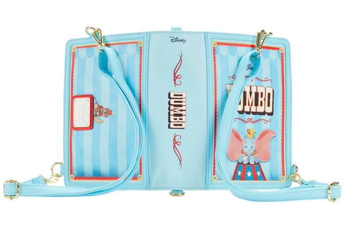 A light blue Disney-themed backpack made of vegan leather, opened to display its interior adorned with Dumbo illustrations. The Blue Dog Posters Dumbo 1941 Book Convertible Crossbody design features Dumbo in circus attire on a red and blue pedestal, with a name tag area, striped background, and gold hardware accents on the adjustable straps.