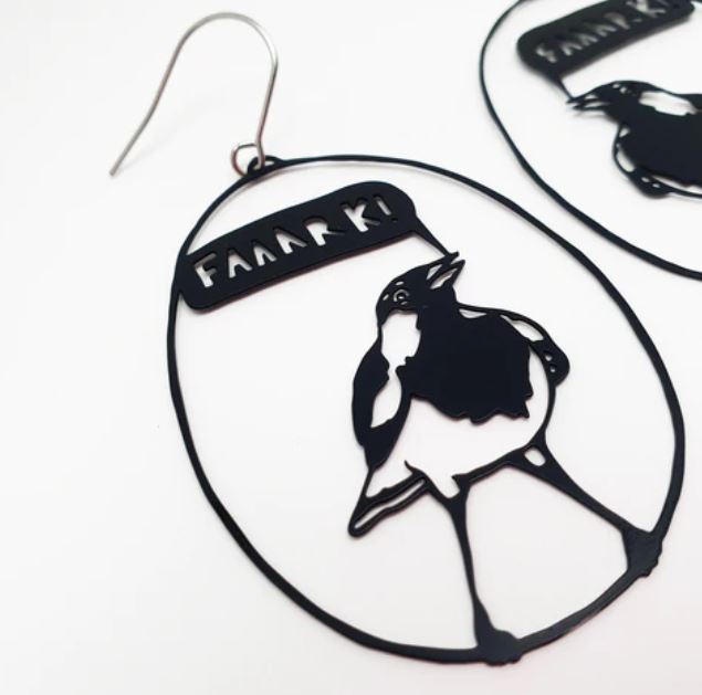A close-up image showcases the Denz Faaaark the Lark Black Earrings by Blue Dog Posters, featuring a bird silhouette with a speech bubble that says "FAAARRK!" Another similar lightweight earring, crafted from recycled stainless steel, is partially visible in the background. The design is minimalist with black outlines on a white background.