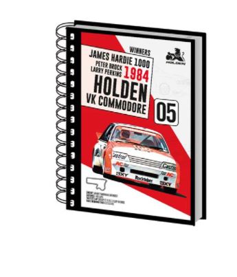 Introducing the Holden 1984 A5 Spiral Note Book by Blue Dog Posters, featuring a vibrant racing car image on the cover complete with text that includes "James Hardie 1000," "Peter Brock," "Larry Perkins," "1984," and "Holden VK Commodore" along with the number "05." The iconic Holden logo is prominently displayed at the top right corner, and the notebook's color scheme features striking red, white, and black hues.