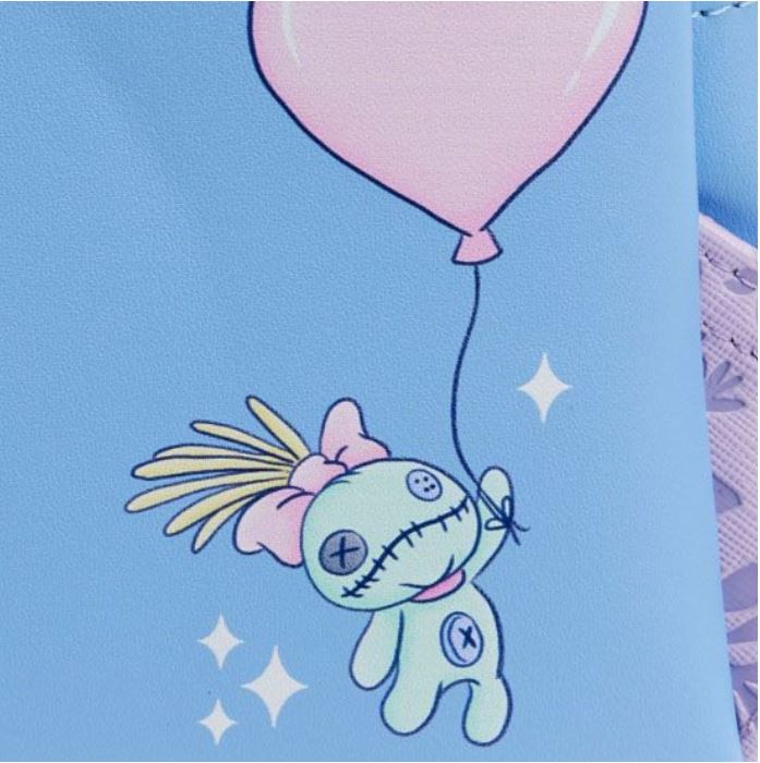 An illustration features an adorable green doll with stitched eyes and mouth, holding a pink balloon. The doll has a pink bow on its head and yellow strands of hair. It’s depicted floating on a light blue background with small white sparkles scattered around, reminiscent of the whimsical designs found on Blue Dog Posters' Lilo & Stitch Heart Stitch Mini Backpack made of vegan leather.