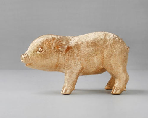 A Blue Dog Posters' Pig Money Box - Gold, featuring a gold-painted piggy bank standing on all fours against a plain gray background. The sculpture boasts detailed features such as ears, eyes, and snout, with a slightly textured surface that lends it a realistic appearance. Coin access is cleverly hidden to maintain its elegance.