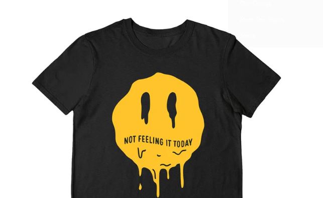 A black t-shirt with a large yellow, melting smiley face on the front. The text "NOT FEELING IT TODAY" is written across the face.