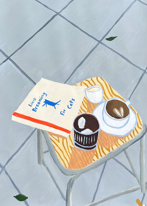 A small table with the "Lucid Dreaming for Cats Vanessa Franklin" art print by Blue Dog Posters, a cup of coffee, dessert, and teacup sits on tiled flooring with leaves—part of a featured artist collection.