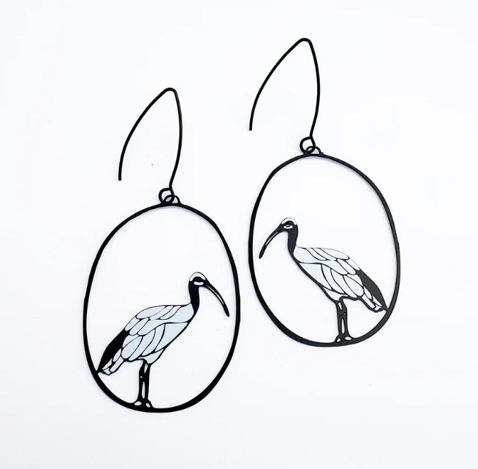 The Sacred Ibis in Black & White Earrings by Denz from Blue Dog Posters feature outlined birds in oval frames, crafted from recycled stainless steel—a unique piece of Aussie jewellery shown on a crisp white background.