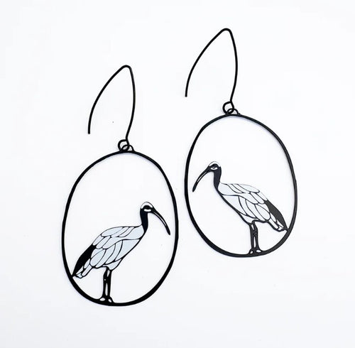 The Sacred Ibis in Black & White Earrings by Denz from Blue Dog Posters feature outlined birds in oval frames, crafted from recycled stainless steel—a unique piece of Aussie jewellery shown on a crisp white background.