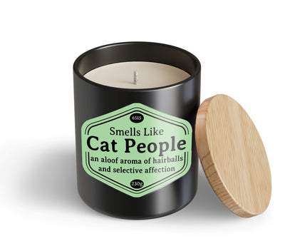 A black Cat People Candle Hustle & Co by Blue Dog Posters with a wooden lid. The label says: "Smells Like Cat People—an aloof aroma of hairballs and selective affection.