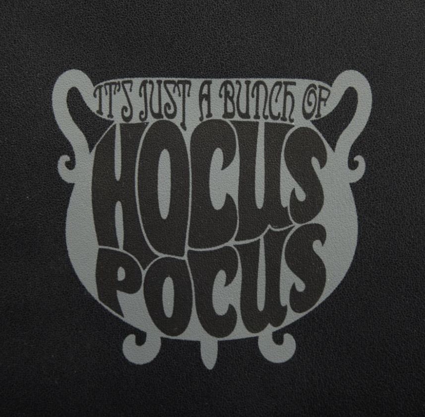 The Hocus Pocus Binx Plush Pocket Mini Backpack by Blue Dog Posters features a black background adorned with the whimsical, vintage-style text "It's just a bunch of Hocus Pocus," nestled inside a stylized cauldron graphic that captures the enchanting essence of the Sanderson Sisters.