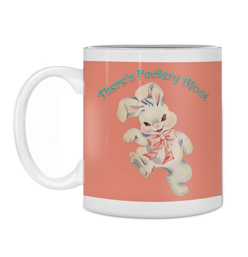 The Hustle and Co Mug - Fuckery Afoot from Blue Dog Posters, part of our Homewares Collection, features a vintage-style illustration of a rabbit with a pink bow. Above the rabbit, playful turquoise text reads, "There's Fuckery Afoot," on a muted reddish-brown background that enhances the ceramic finish.