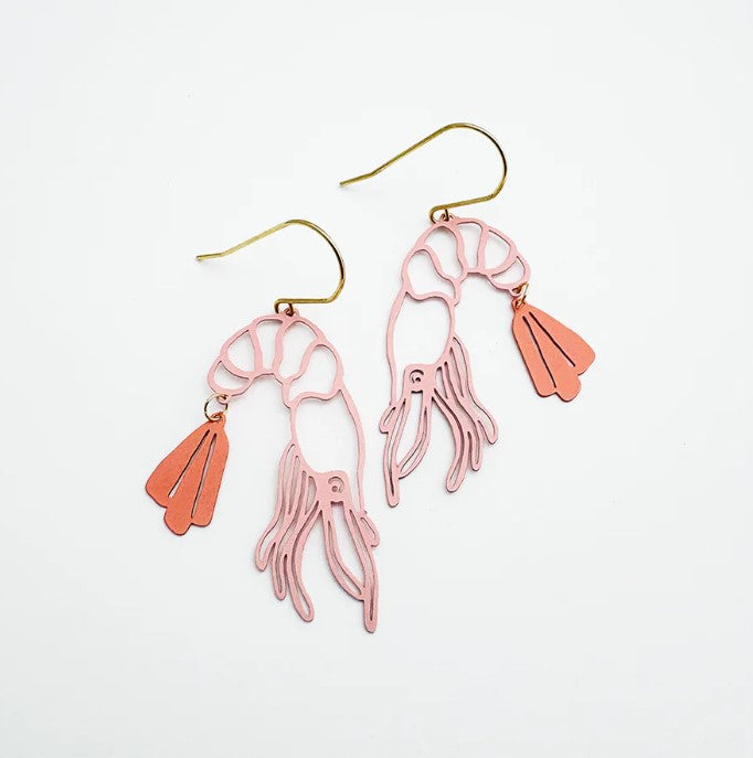 The Midi Prawn Dangles in Coral by Denz from Blue Dog Posters feature pink shrimp shapes with gold hooks and an orange tail fin, crafted from recycled stainless steel—a stylish summer Christmas accessory on a white background.