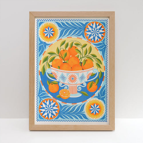The "Orange Bowl Riso Print" by Printer Johnson for Blue Dog Posters features oranges in a white bowl, set among blue, yellow, and orange patterns. Eco-friendly soy inks are used. Four circular corner motifs complete the London-printed artwork.