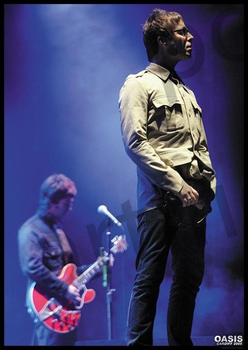 Under dramatic lighting, two musicians perform on stage: one stands in a light jacket, another plays a red electric guitar. The "MUS 347 Oasis - Cardiff 2005" name appears in the corner of this striking rock poster.
