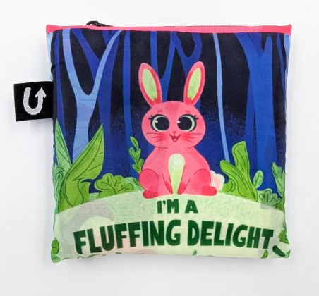 The Funny Bunny Foldable Tote Bag by Blue Dog Posters is made from recycled PET, featuring a pink rabbit among green plants on a blue forest background with "I'M A FLUFFING DELIGHT" text.