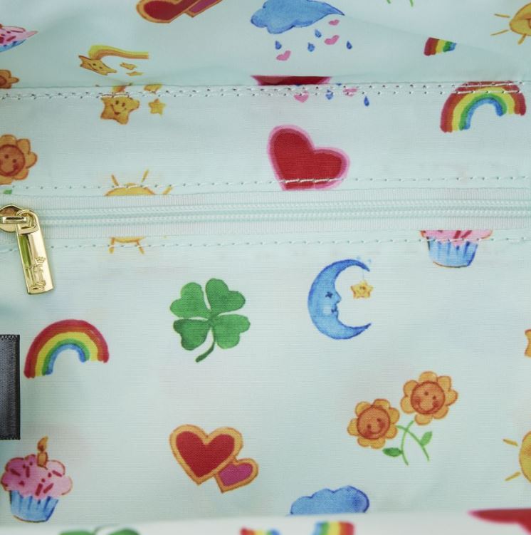 A close-up of the Care Bears & Cousins Lunchbox Crossbody by Blue Dog Posters showcases a vibrant pattern of colorful illustrations, including rainbows, hearts, crescents, shamrocks, suns, flowers, cupcakes, clouds, and star shapes. Made from vegan leather with a soft pastel background and featuring a gold zipper.