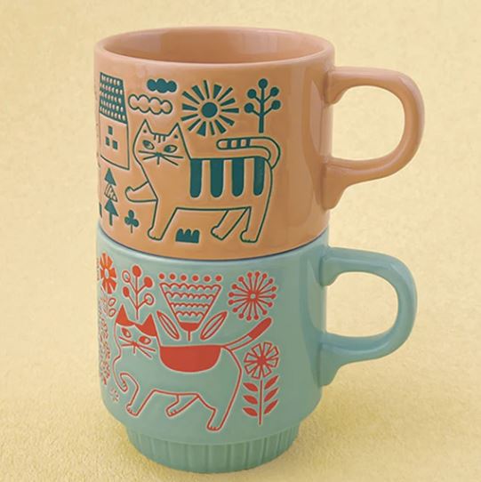 Two stacked Blue Dog Posters Cat Flower Garden Aqua & Orange Japanese Mugs, featuring playful feline and floral designs, bring Japanese zakka charm to a pale yellow backdrop.