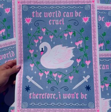 The World Can Be Cruel A3 Risograph by Amy Hastings (Blue Dog Posters) features a white swan with pink flowers in a heart, two crossed swords, and the quote: "the world can be cruel. therefore, i won't be." Printed on recycled coffee cup paper.