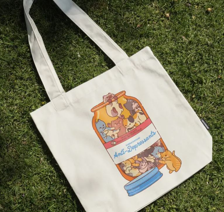 The Blue Dog Posters Anti-Depressants Cat Edition Tote Bag, made of white cotton canvas, features a playful jar of colorful cats and brings cheerful style to your day.