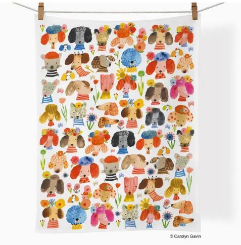 The Werkshoppe Tea Towel Dog Earred by Blue Dog Posters hangs on a line, displaying cartoon dogs in striped shirts and floral crowns, surrounded by small flowers on a white background—a fun, dog-themed kitchen towel.
