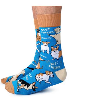 A pair of feet in Blue Dog Posters' Dog Parent Socks, blue with tan cuffs, heels, and reinforced toes, decorated with playful dog illustrations and the words "BEST FRIEND" and "WOOF" scattered across the design.