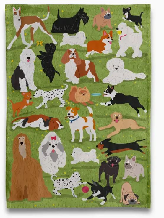 The "Dogs at the Park Tea Towel" by Blue Dog Posters features playful illustrations of pugs, dalmatians, bulldogs, and more on green grass—an ideal oversized decor piece or unique gift for any dog lover.