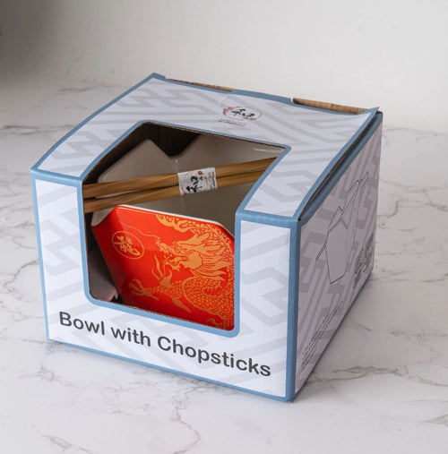 The Blue Dog Posters Takeout Box Serving Bowl With Chopsticks GOLD DRAGON features a microwave safe red ceramic bowl with a gold dragon design and reusable chopsticks, all visible through a clear window in the packaging.