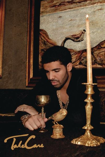 A man sits at a table adorned with a tall candle, a golden goblet, and a small golden statue of a bird. He appears contemplative and is dressed in dark clothing with gold jewelry. A "Drake - Take Care" Hip Hop Poster from MUS 167 is displayed at the bottom left of the image.