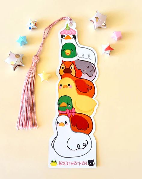 The Bookmark Duck Stack by Jess Chen, from Blue Dog Posters, features a stack of cute cartoon ducks with playful expressions, topped with a tassel and pastel origami stars—a delightful take on the classic bookmark.