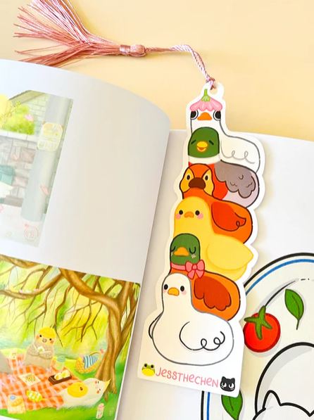 The Bookmark Duck Stack by Jess Chen from Blue Dog Posters is a colorful illustrated bookmark showing cute ducks stacked in fun poses, topped with a pink tassel—ideal for marine life fans and stationery lovers.
