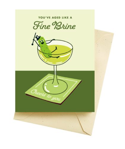 Celebrate with the Fine Brine Martini Birthday Card by Blue Dog Posters, featuring a cheerful cartoon pickle in a cocktail glass and the message "You've aged like a Fine Brine." Includes coaster with "Cheers to you" and envelope.