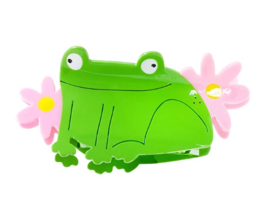 The Princess Frog Hair Claw by Blue Dog Posters is a green acetate clip shaped like a cartoon frog, adorned with pink flowers featuring yellow centers—a playful jewelry accessory, displayed on a white background.