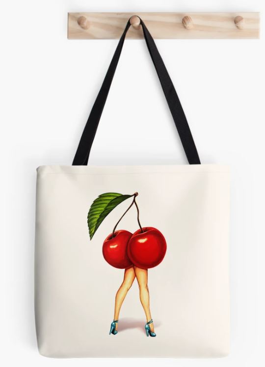 The Blue Dog Posters "Fruit Pin Up Cherry Girl Tote Bag" with sturdy black handles hangs on a wooden peg rack. The white tote bag features a humorous sublimation printed illustration of two cherries with a green leaf, where the cherry stems are depicted as human legs wearing high heels.