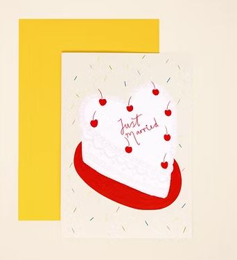 The Heart Cake Wedding Card by Blue Dog Posters features a retro heart cake with cherries and “Just Married” in red, on a light sprinkled background and paired with a yellow envelope—a fun, modern way to celebrate newlyweds.