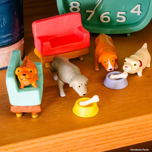 The Hello in the World Vol 7 Neil Ewing Blind Box by Blue Dog Posters features four collectible mini toy dogs with two colorful couches, dog bowls with bones, and a green clock—ideal for collectors and dog lovers.