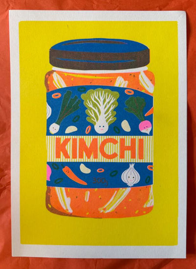 Kimchi Riso Print by Naomi Wilkinson Illustration for Blue Dog Posters features a vibrant jar of kimchi with a veggie label on a yellow background. "KIMCHI" stands out in bold orange, inspired by Risograph prints.