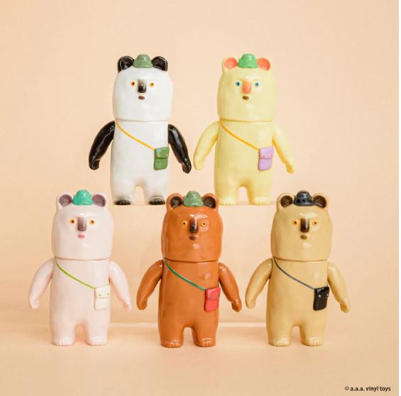 Five colorful Kurikun Figure Blind Box toys by Blue Dog Posters, each with a hat and crossbody bag, are displayed in two rows on a beige background. These mini figures have round ears and simple faces.