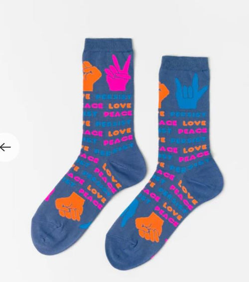 Blue Dog Posters’ Love Peace Persist Womens Socks are blue cotton crew socks featuring colorful hand signs and the words "resist," "persist," "peace," and "love" in orange, pink, and blue for stylish comfort.