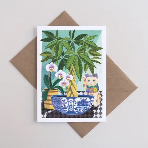 The Money Tree Greeting Card by Blue Dog Posters features a blue bowl with a leafy plant, a yellow vase with white orchids, and a lucky cat on a checkered surface. Includes an A6 recycled envelope.