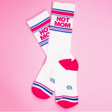 The Blue Dog Posters Hot Mom Gym Crew Socks feature blue and pink stripes with "HOT MOM" in bold pink letters, plus matching pink toes and heels, all shown on a vibrant pink background.