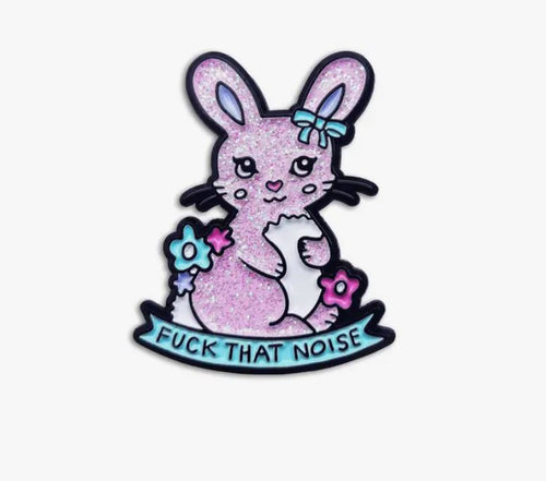 The Noise Rabbit Enamel Pin by Blue Dog Posters features a glittery pink rabbit cartoon with a blue bow on its ear, holding blue and pink flowers. Below the rabbit, there's a light blue ribbon with black text that reads, "FUCK THAT NOISE". The design is set against a plain white background, making this quirky enamel pin truly unique.