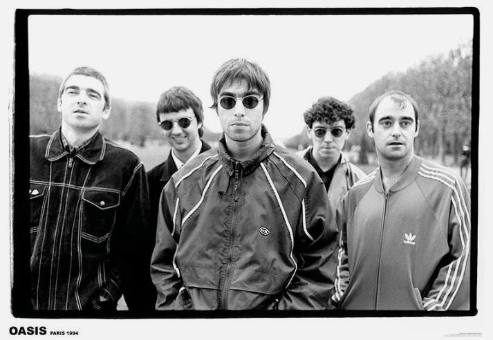 Oasis - Paris 1994 by MUS 137 features five men outdoors in a black-and-white photo, all in casual jackets and sunglasses. The central figure faces the camera. An iconic addition to any music collection or as a large regular poster.
