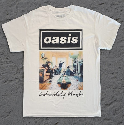 The Official Oasis Definitely Maybe T-Shirt WHT XL by Blue Dog Posters shows the band in a living room with the album title in cursive. Laid flat on a gray surface, this shirt is perfect official merchandise for true Oasis fans.
