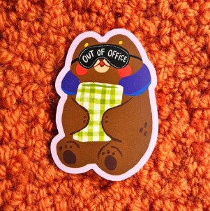 The Out of Office Vinyl Single Sticker by Blue Dog Posters features a cartoon bear in sunglasses, holding a green checkered mug on an orange surface—perfect waterproof decor for your laptop or water bottle.