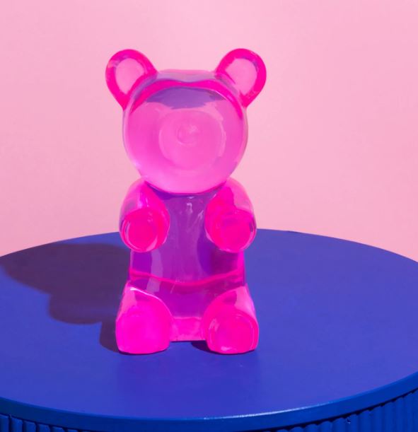 Barry Bear Blue Resin by Blue Dog Posters features a translucent pink bear sitting upright on a round blue base against a light pink background, making an adorable gummy bear decor or fun paper weight.