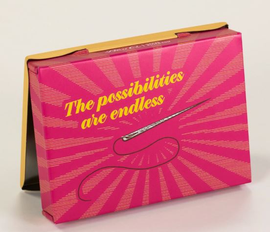 The Pins and Needles Small Tin by Blue Dog Posters is a pink storage box with yellow text saying "The possibilities are endless" and features a sewing needle, thread illustration, and radiating lines on a crafting-inspired background.