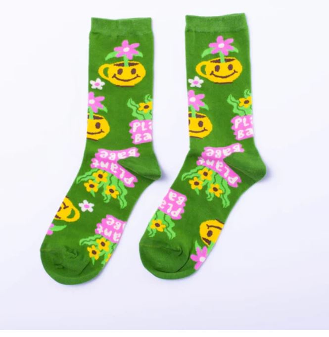 Blue Dog Posters' Plant Babe Women's Socks feature green cotton with yellow smiling flowers, pink floral accents, and "PEACE BABE" in pink and white text for a cheerful style. Add comfort and fun to any outfit with these soft socks!.