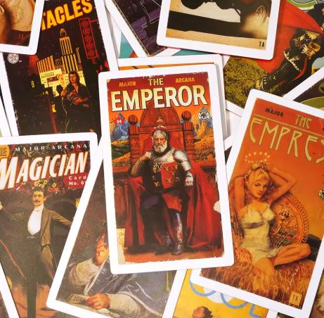 A vibrant display of The Pulp Tarot Cards by Blue Dog Posters showcases vivid illustrations, with "The Emperor" card in the center, surrounded by "The Magician" and "The Empress"—an ideal set for tarot readings.