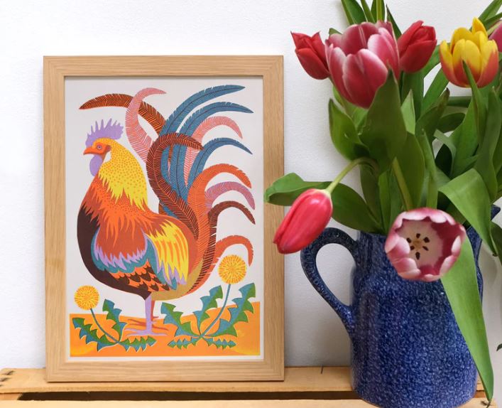 The "Rooster A4 Risograph" by Vicki Johnson from Blue Dog Posters features a vibrant rooster illustration beside a blue jug of tulips, printed with eco-friendly soy-based inks on a plain white background.