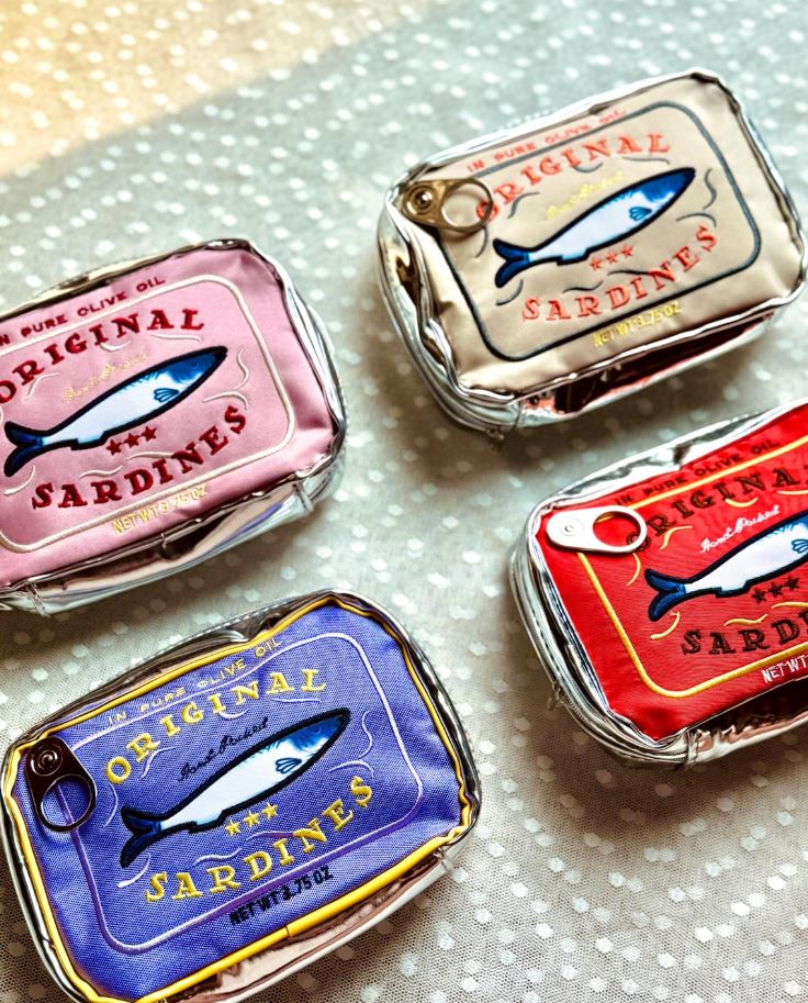 The Sardine Tin Bag Green by Blue Dog Posters is a novelty small bag designed to resemble a colorful sardine can, featuring playful fish illustrations and charming sardine branding.