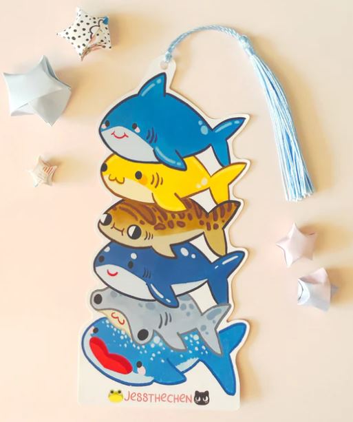 The Blue Dog Posters Bookmark Shark Stack features six vibrant cartoon sharks and a light blue tassel, making it a fun addition to your cute stationery collection. Origami stars complete this charming celebration of marine life.